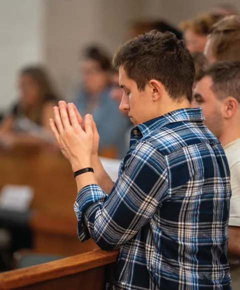 Student praying in Christ the King Chapel.